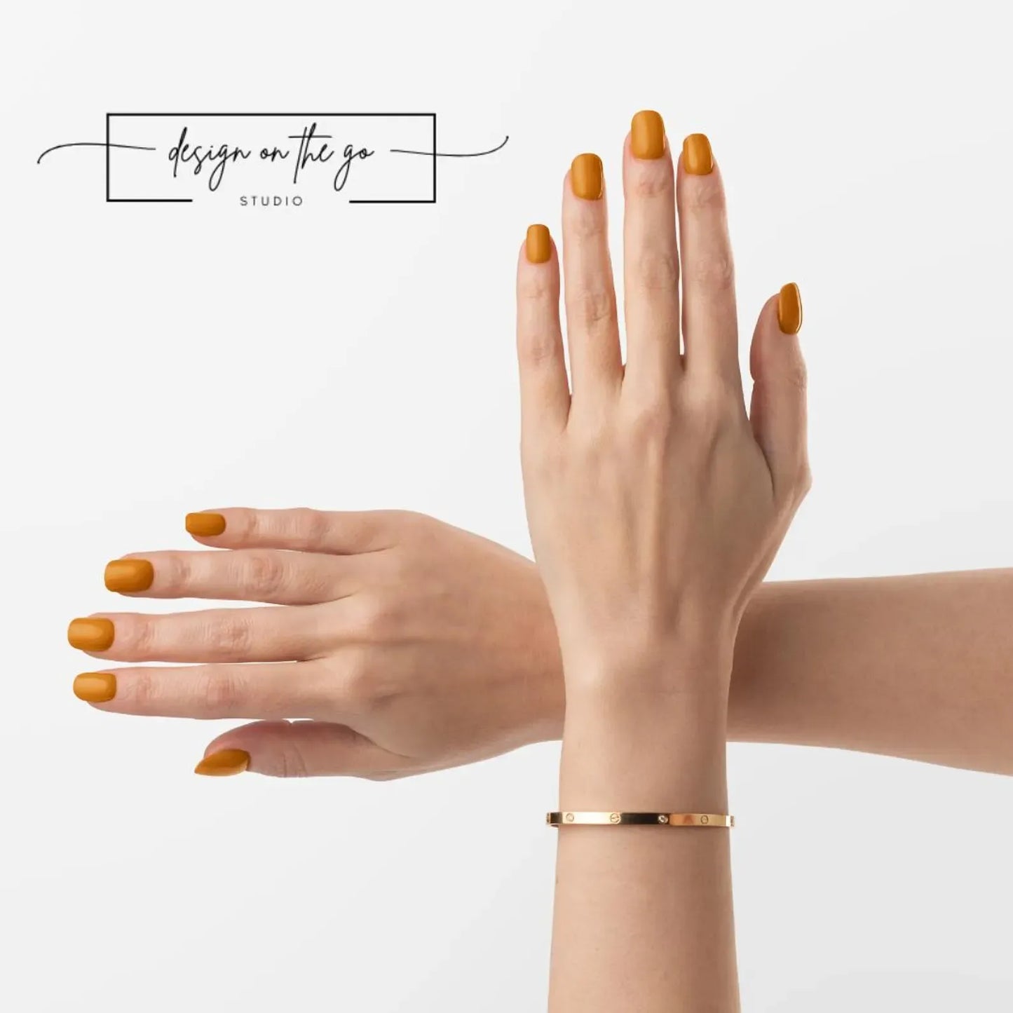 Two hands with orange nail polish and a gold bracelet on a light gray background.