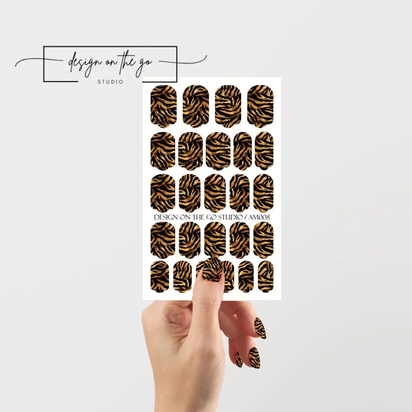 Sheet of zebra print nail art stickers held by a hand with a white background.