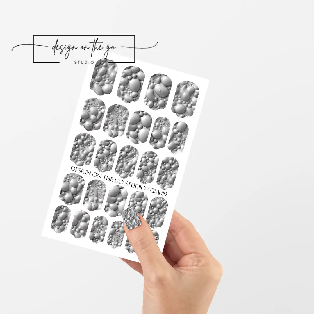 #type_manicure single hand with beautifully manicured nails with nail wraps holding full nail wraps sheet.