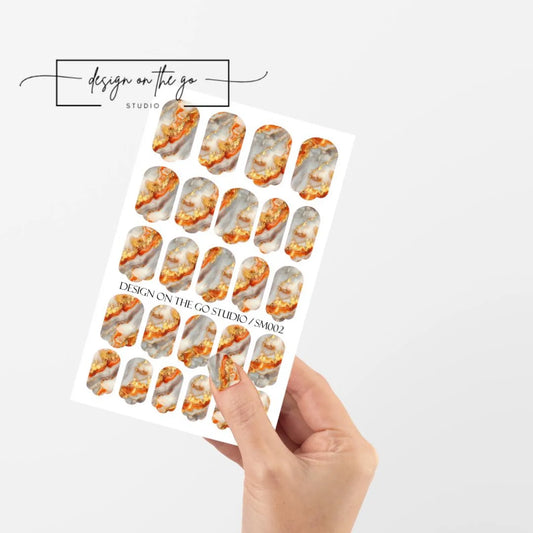 Sheet of nail art stickers with marble design held by a hand on a white background
