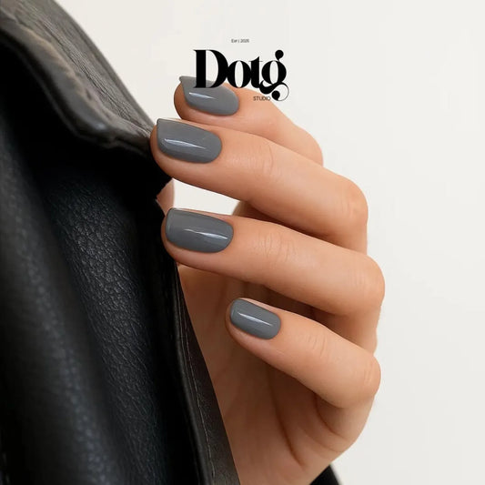 Hand with gray nail polish holding a black leather bag, Doto Studio logo visible