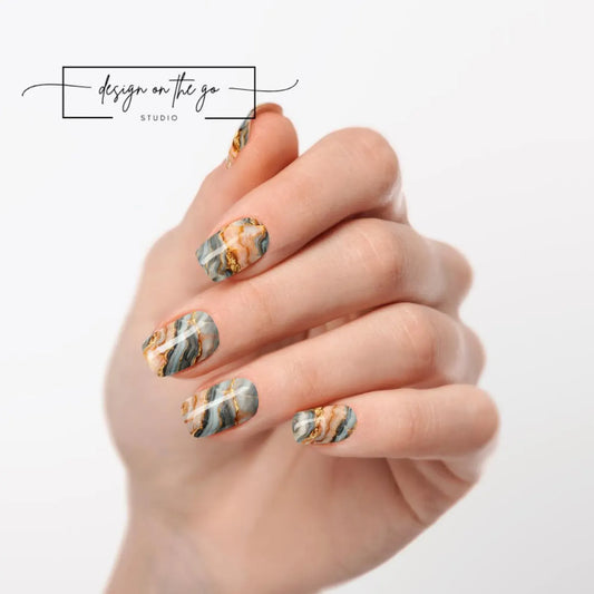 Hand with marbleized nail art on a white background, featuring 'Design on the Go Studio' logo.