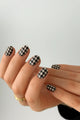 #type_manicure Hand with houndstooth patterned nail wraps nails on a plain background