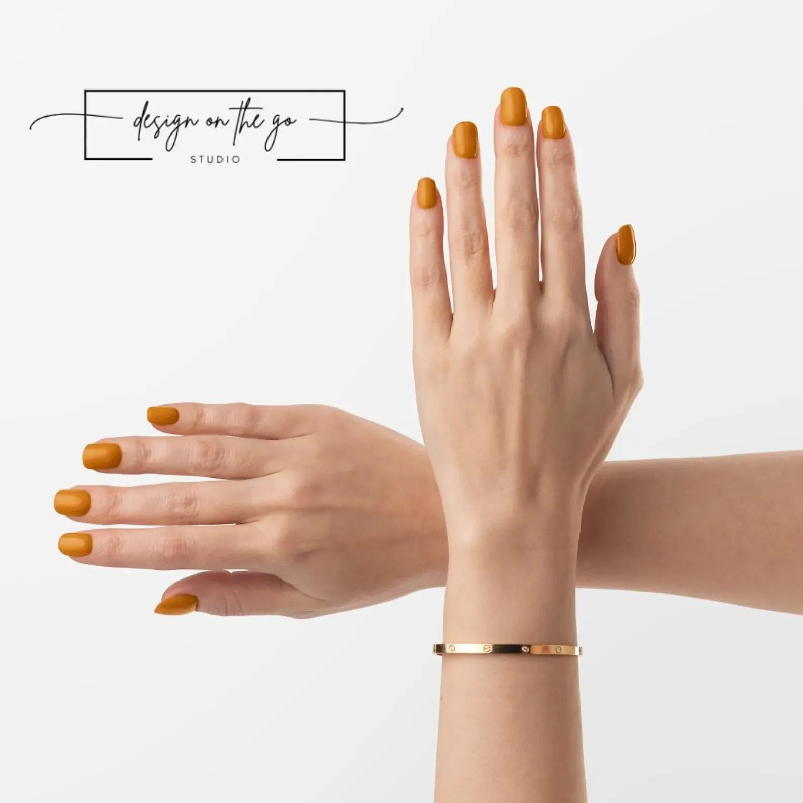 Two hands with orange nail polish and a gold bracelet on a light gray background.