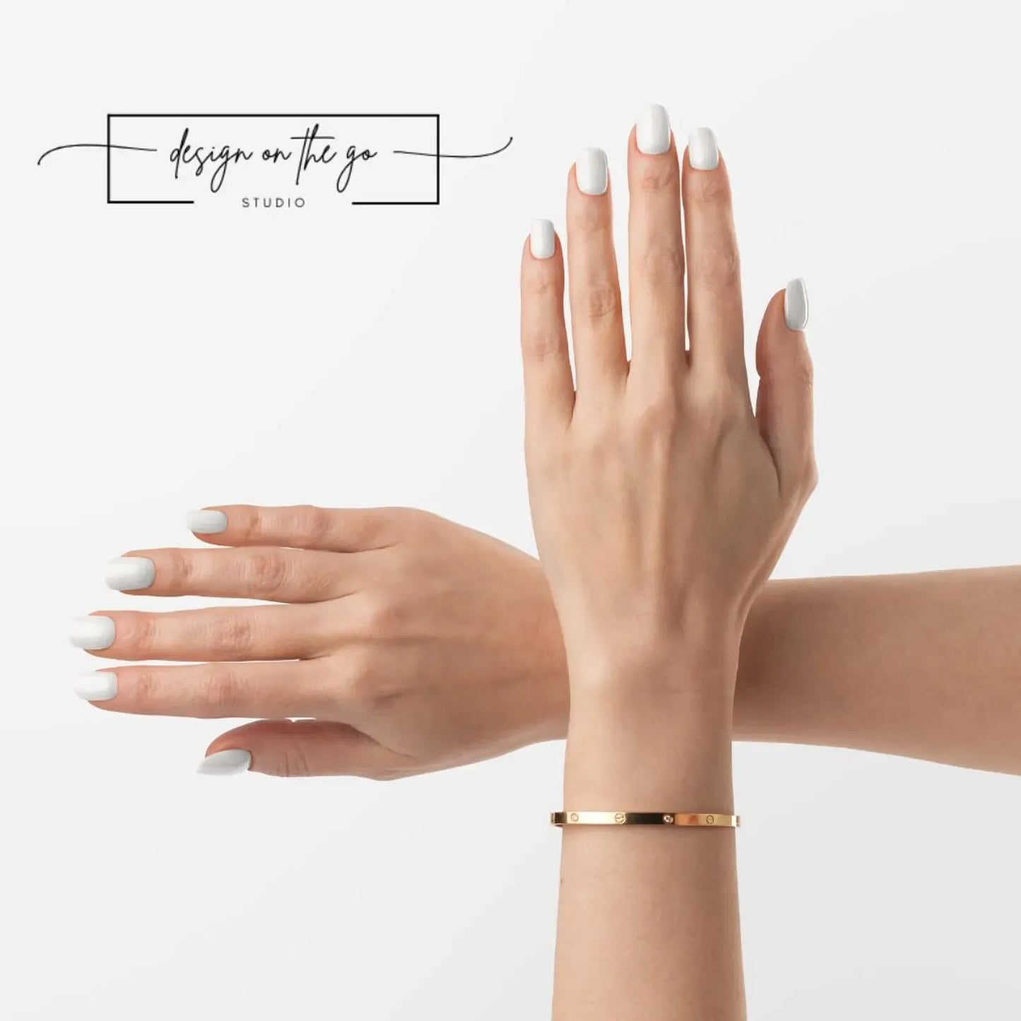Gold bracelet on a hand with white nail polish against a light background
