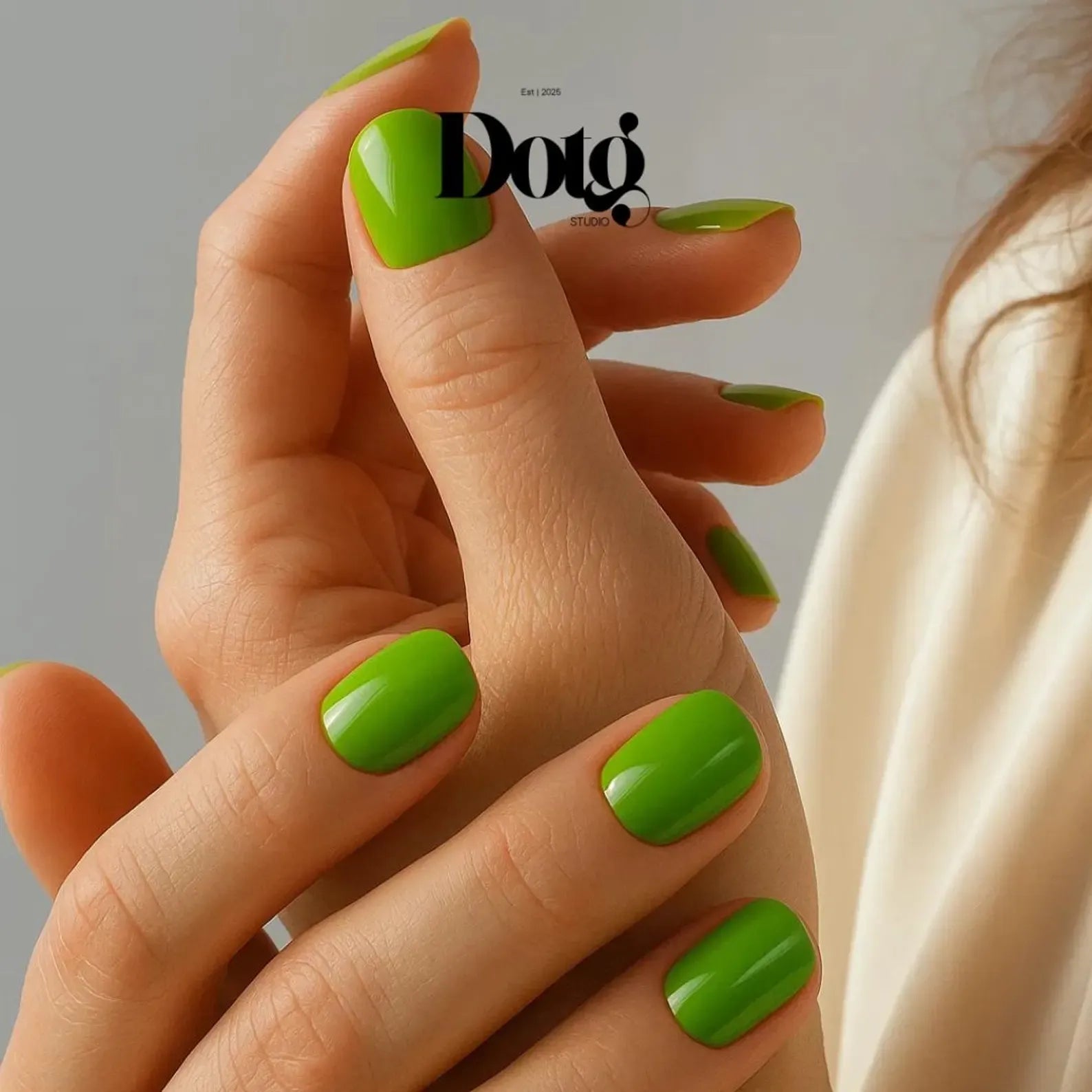 Close-up of a hand with green nails against a neutral background, featuring the Dotq brand.
