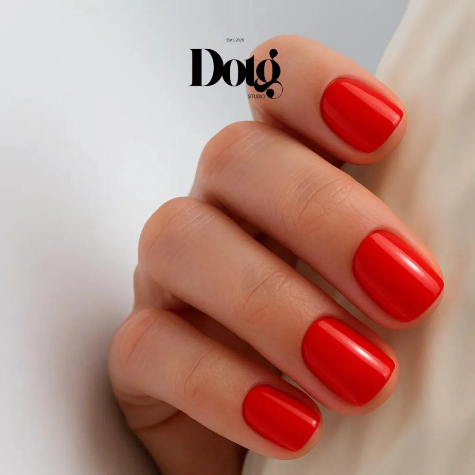 Hand with red nail polish on a white background, featuring the Dotg Studio brand.