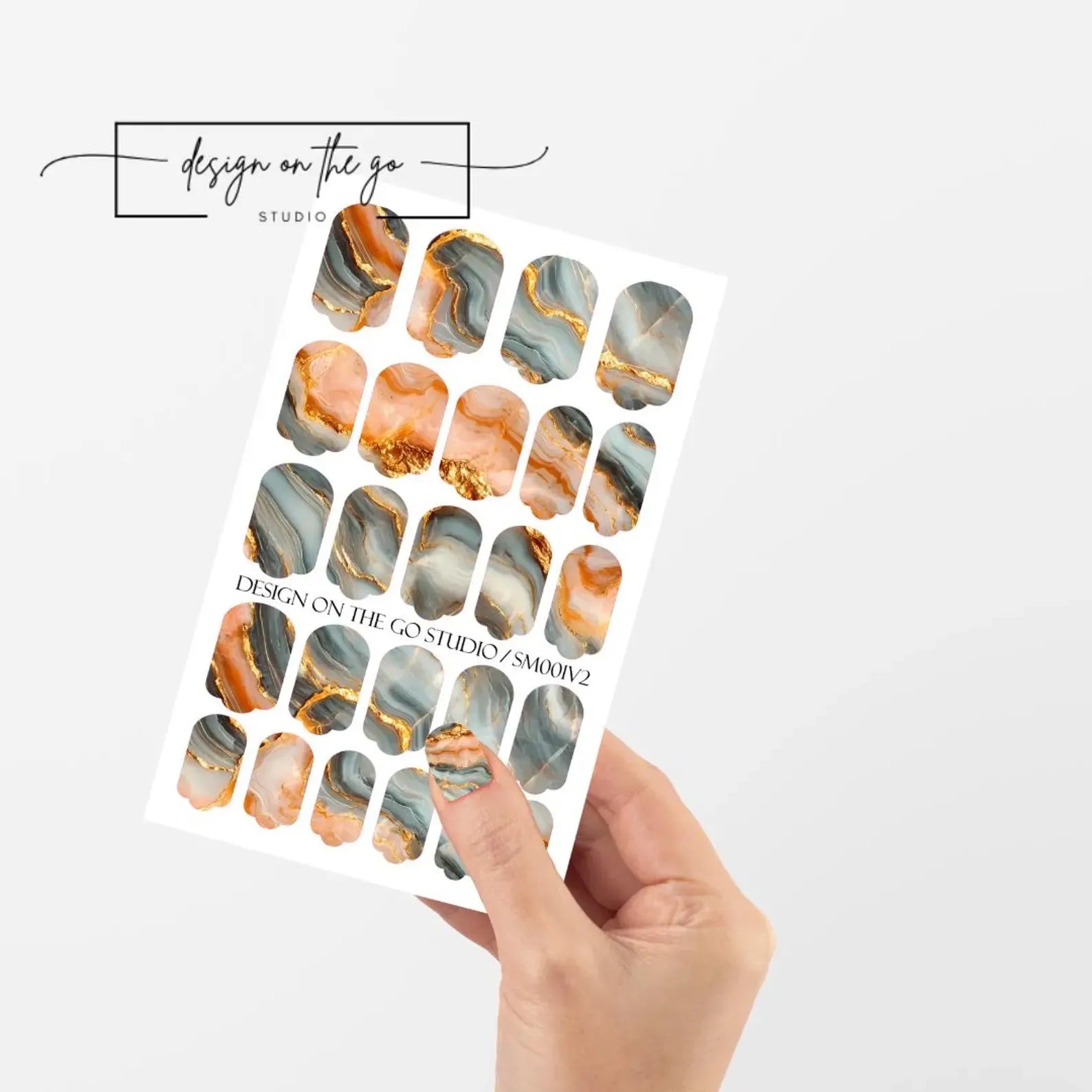 Sheet of marbled nail art stickers held by a hand on a white background