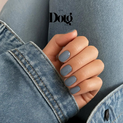 Hand with gray nail polish wearing a denim jacket, featuring the Dotg Studio logo.