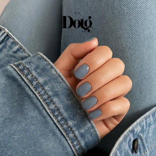 Hand with gray nail polish wearing a denim jacket, featuring the Dotg Studio logo.