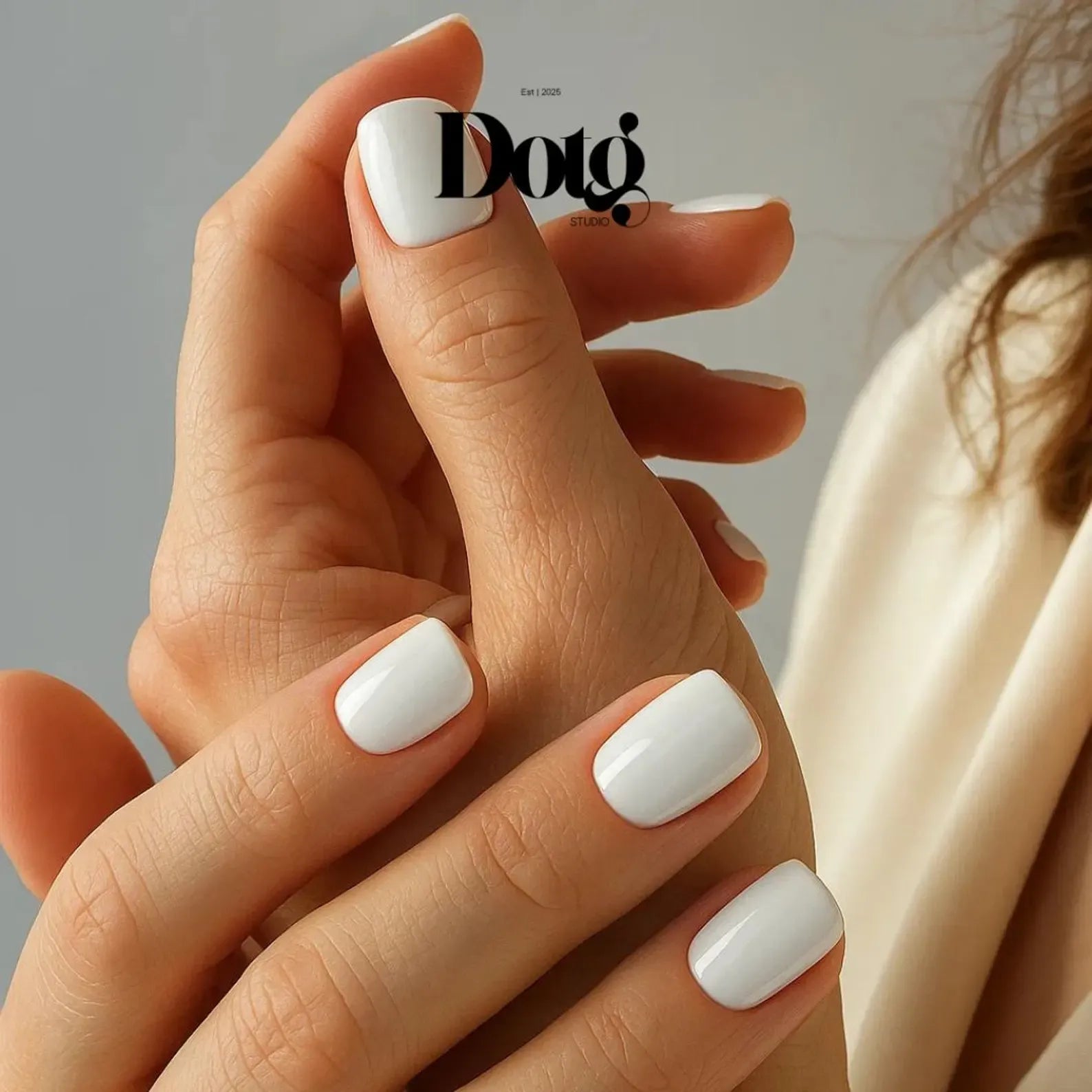 Hands with white nail wraps on a neutral background, featuring the Dotg Studio logo.