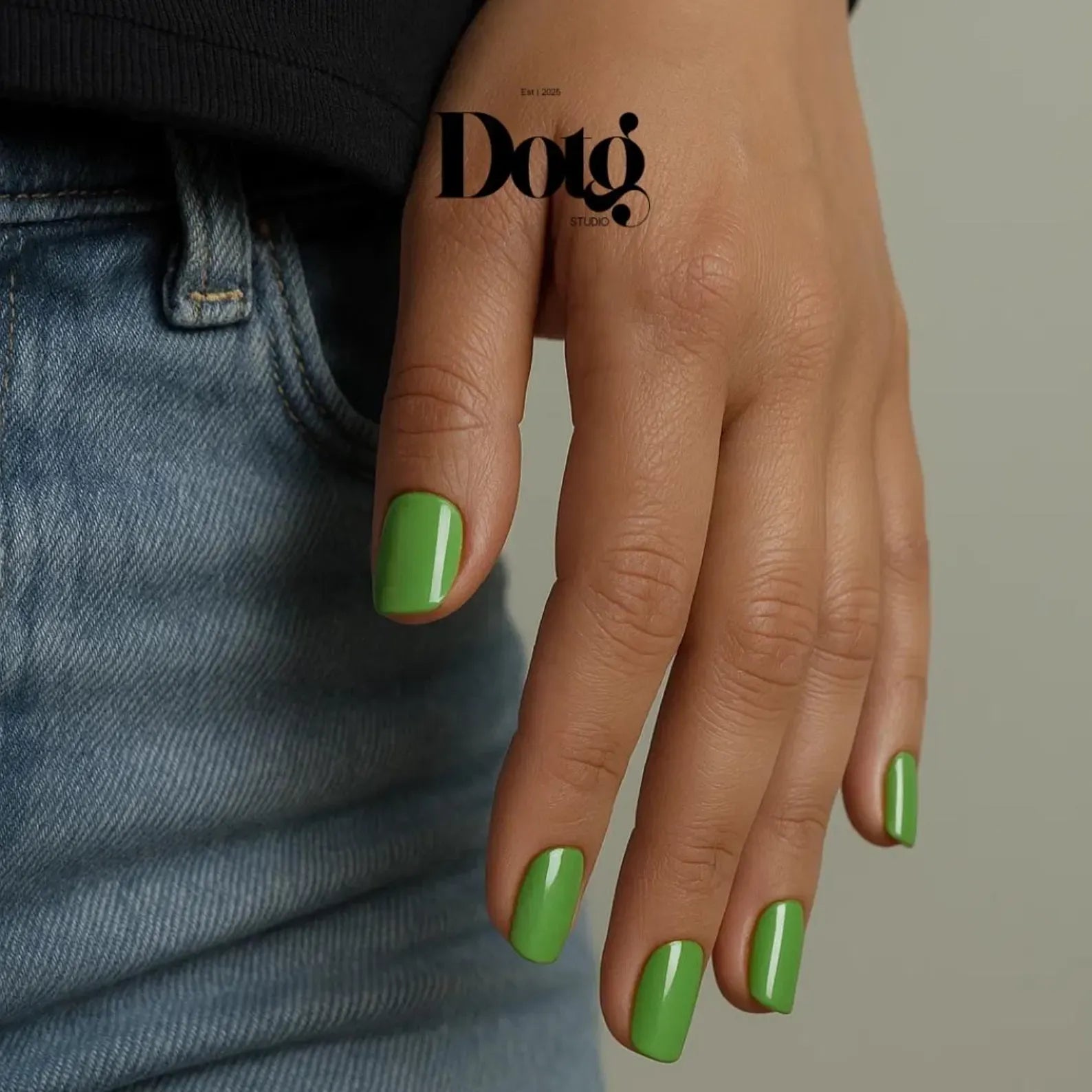 Hand with green nails wearing a black sleeve, with 'Dotg Studio' branding.