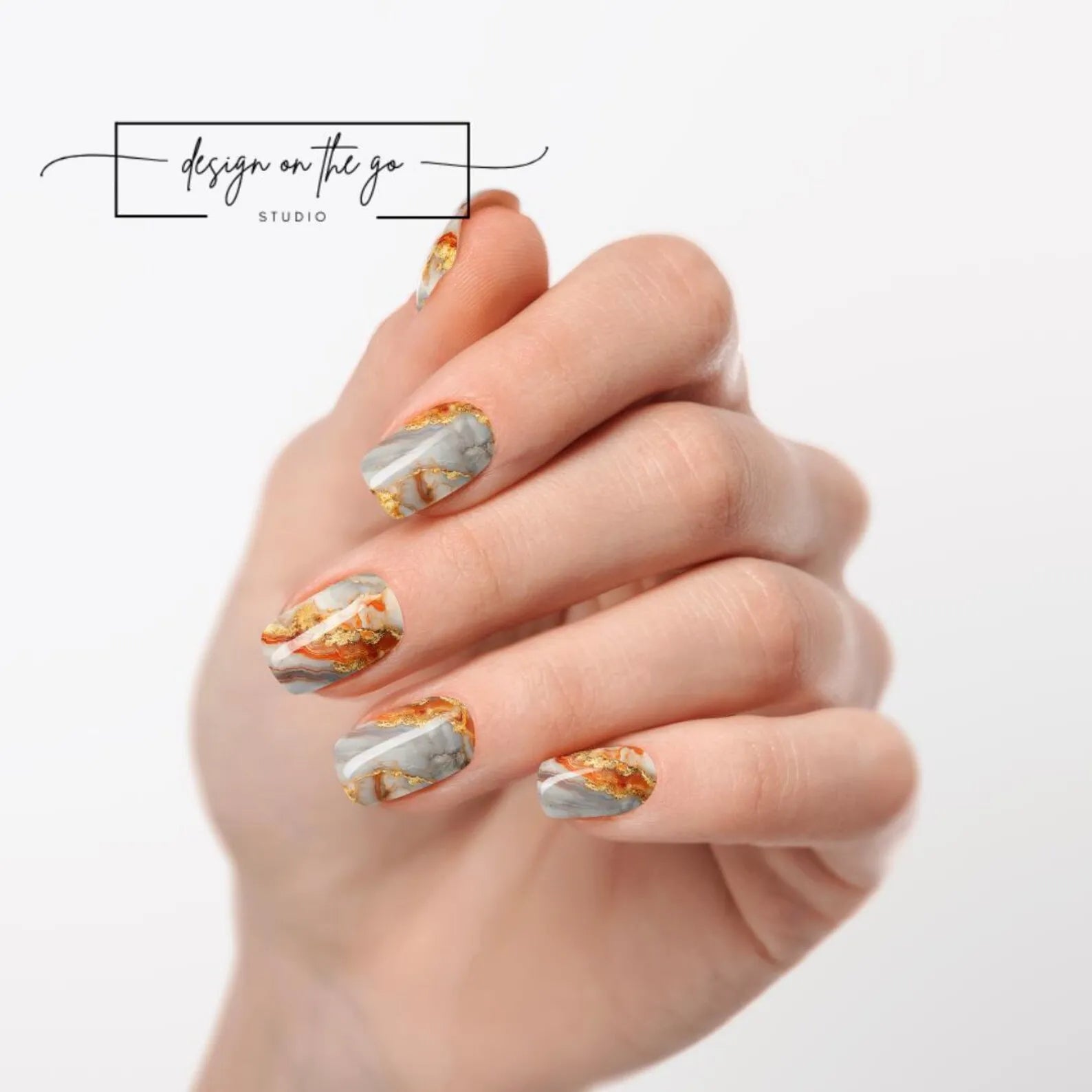 Hand with marbleized nail art on a white background, featuring 'Design on the Go Studio' logo.