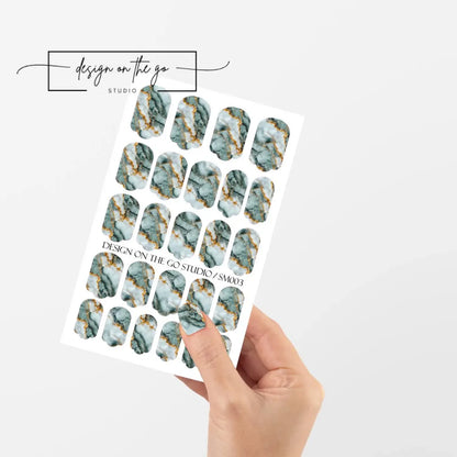 Sheet of green marble nail art stickers held by a hand on a white background