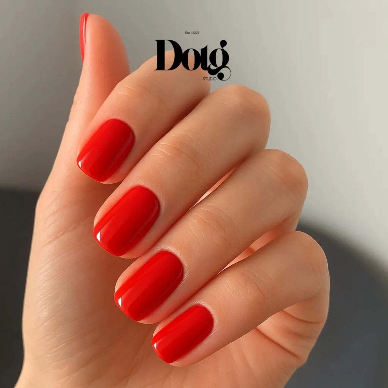 Hand with red nail polish on a neutral background, featuring the Dotg Studio logo.