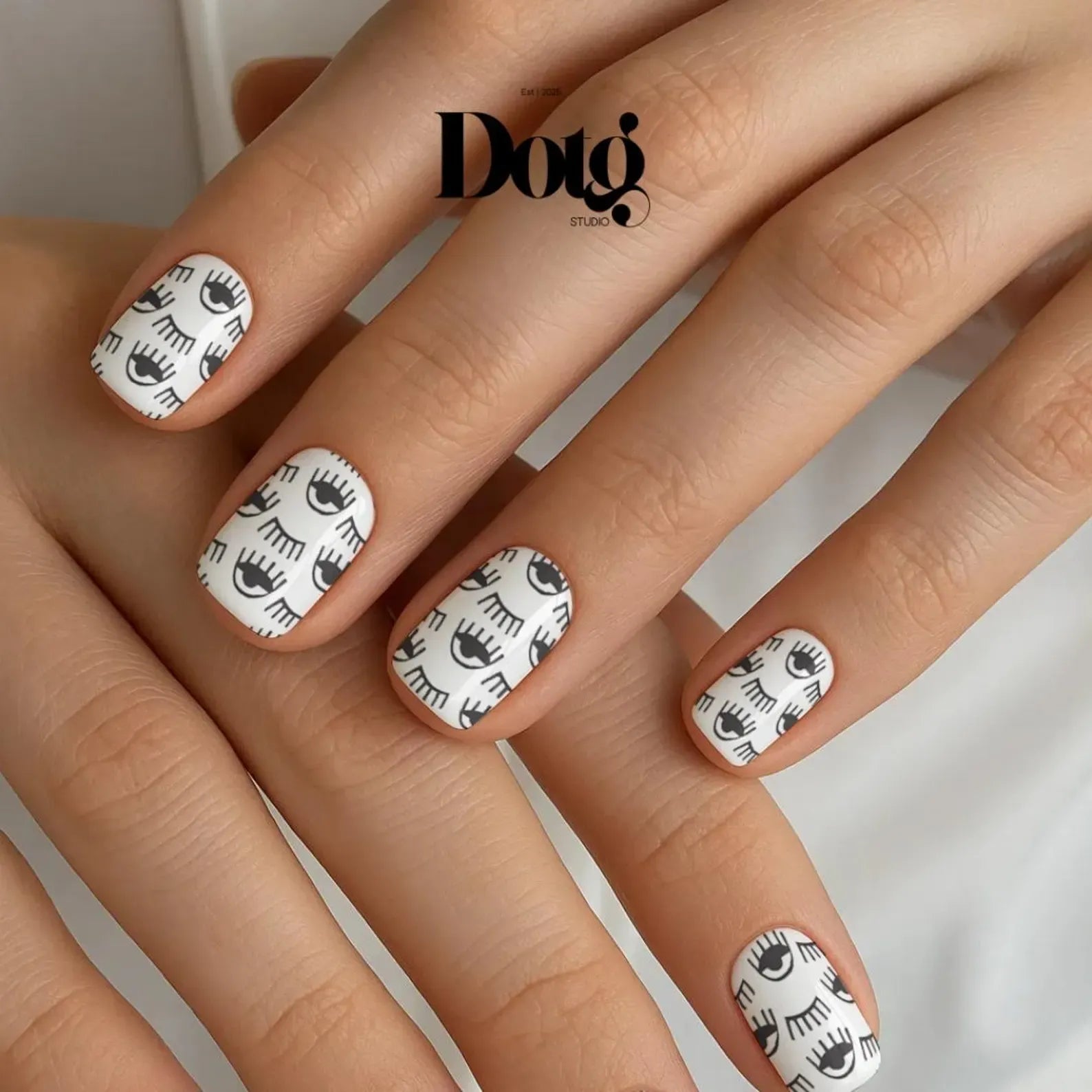 Nails with eye pattern design on a neutral background, featuring the Dotg brand.