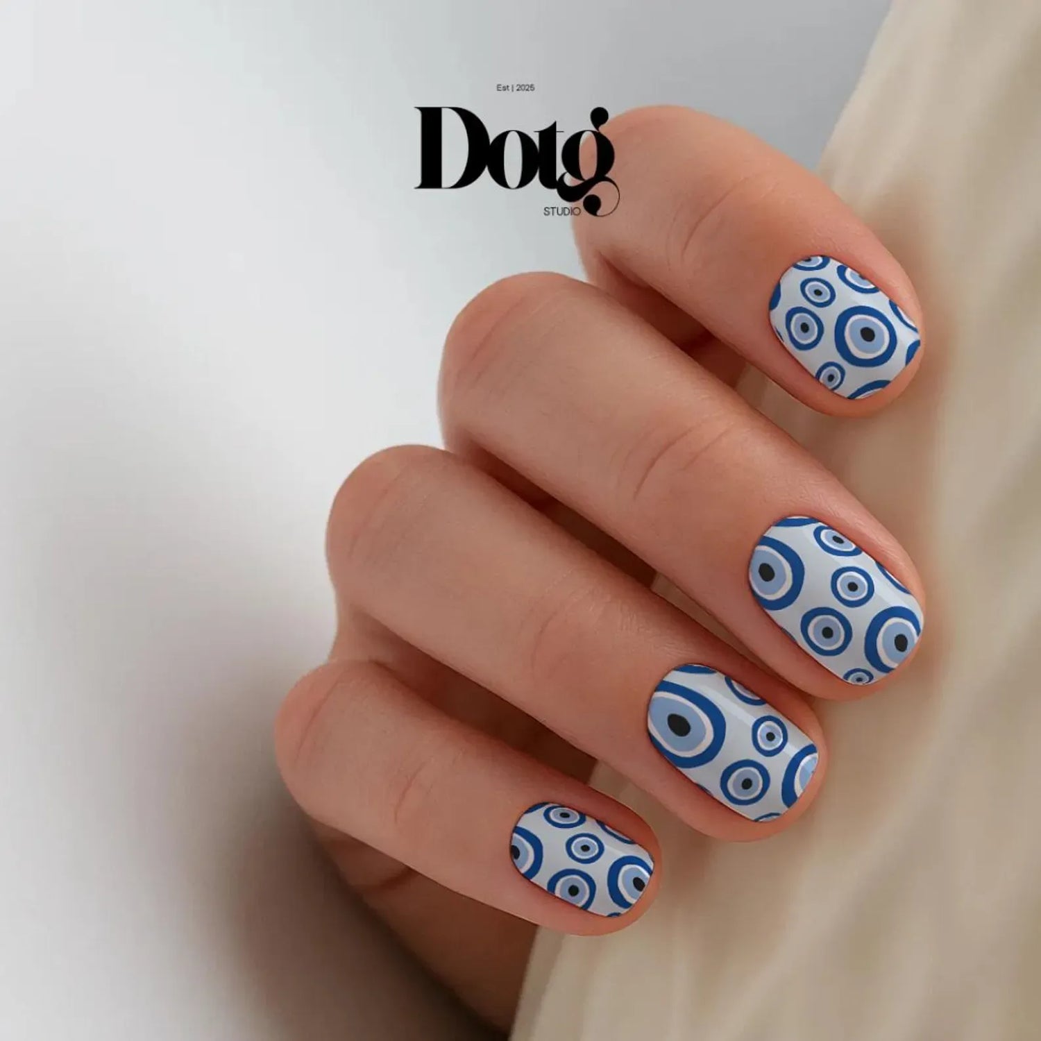 Hand with blue and white circular nail art on a plain background
