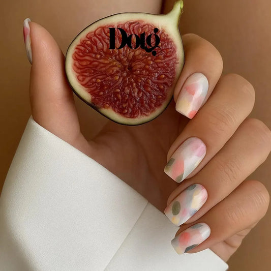 Manicured Hand holding a sliced fig against a neutral background