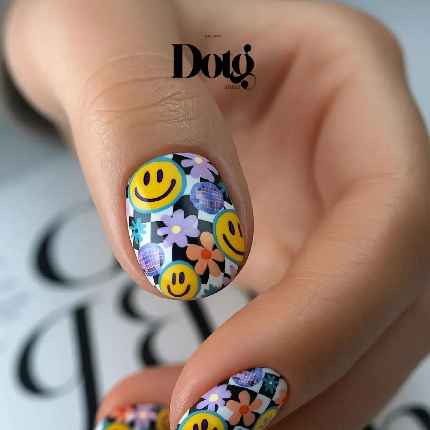 Nail art nail wraps with smiley faces and flowers on a neutral background.