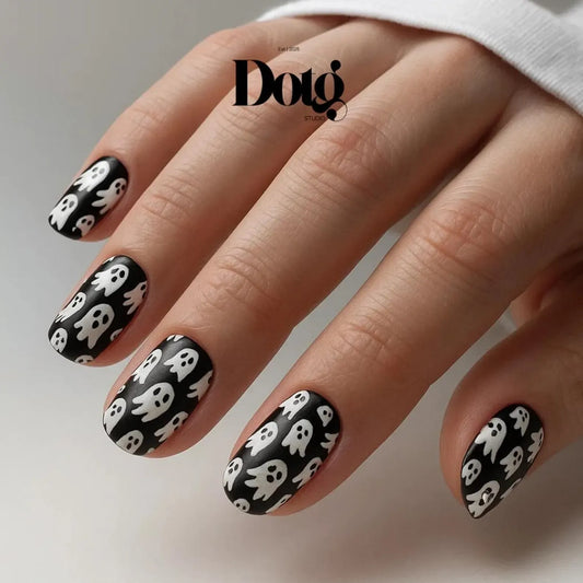 #type_manicure manicured hand with black and white spooky ghosts nail wraps on white background